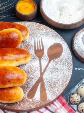 Sobada PeraĹźki top view tasty dinner rolls fork spoon imprint powdered sugar wood board quail eggs oil bottle turmeric flour bowls table
