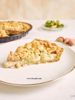 vertical shot of a slice of crispy rhabarbar cake tart on a white plate with some fruits