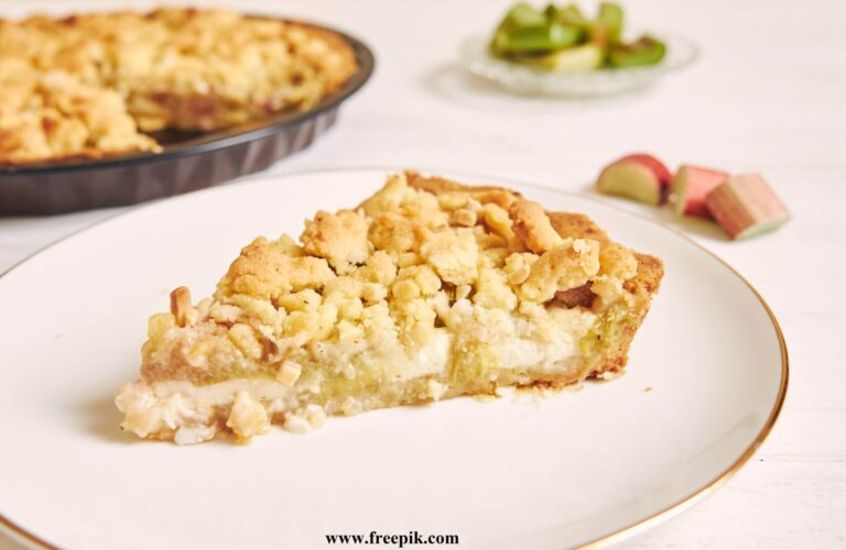 vertical shot of a slice of crispy rhabarbar cake tart on a white plate with some fruits